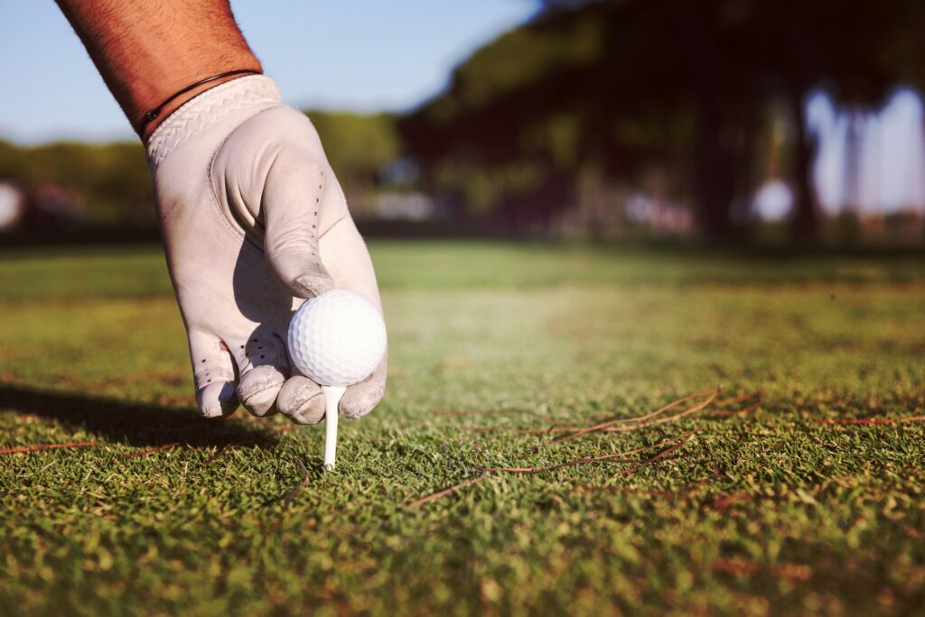 close up of golf players hand placing ball on tee