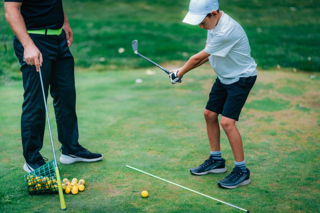 Golf – Personal Training. Golf Instructor Teaching Young Boy How to Play Golf.