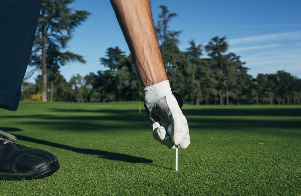 Golfer puts the golf ball on a tee