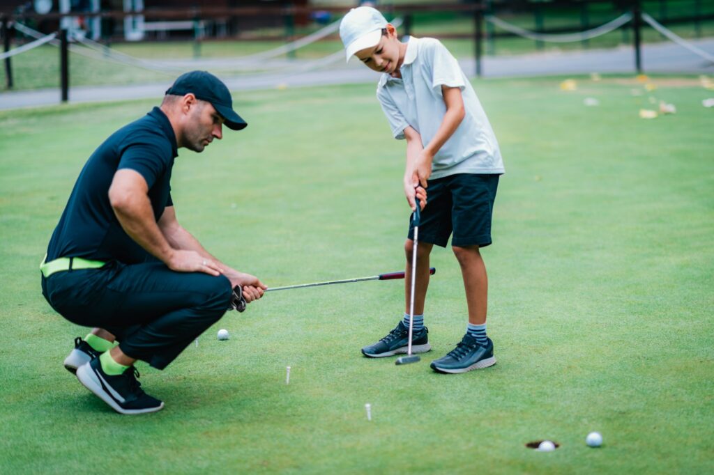 Learning Golf. Boy practicing putting with instructor