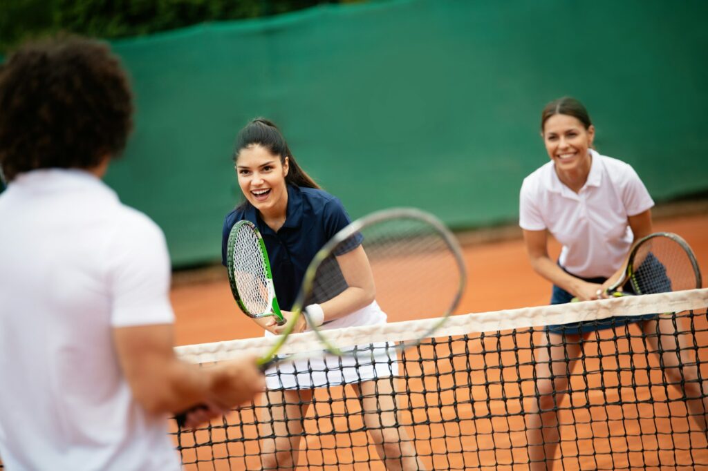 Young happy fit women playing tennis on tennis court